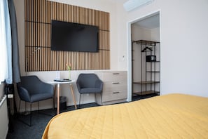 A hotel room with a bed, two chairs, a small table, a TV, and a wardrobe. - Hotel Oepkes (West-Terschelling)