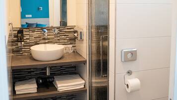 A bathroom with a white sink, a mirror, a towel rack, and a toilet paper holder.