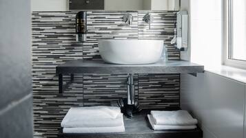 Un baño moderno con un lavabo blanco grande, un dispensador de jabón para manos y un perchero para toallas.