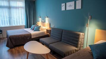 Ett hotellrum med två sängar, en soffa, ett bord och konstverk på väggen.