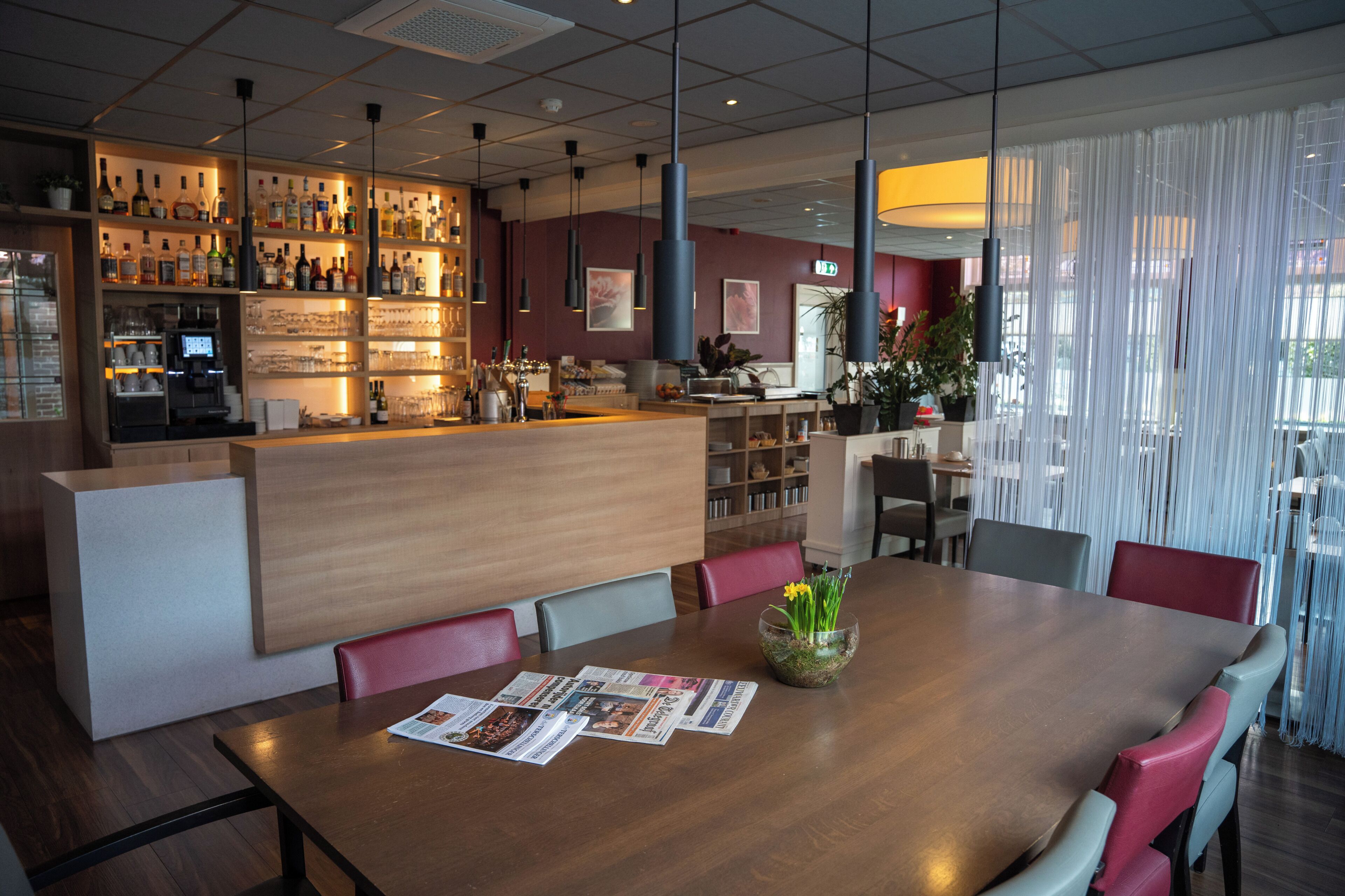 Un restaurante con zona de bar, mesas y sillas de madera.
