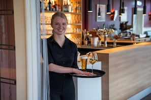 A bar area with a counter, glasses, and bottles. - Hotel Oepkes (West-Terschelling)