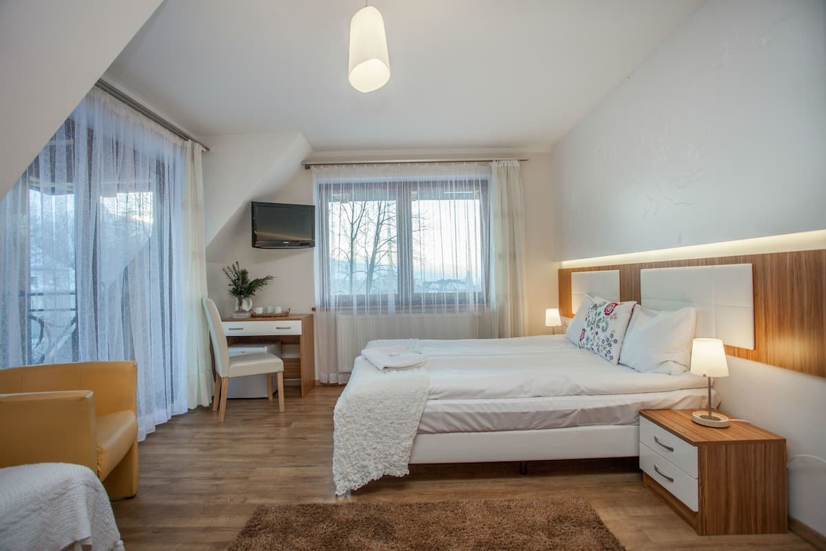 Une chambre à coucher comprenant un lit, une table de chevet, une chaise, un bureau et un téléviseur fixé au mur.
