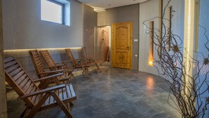 Um espaço de spa com espreguiçadeiras de madeira, uma porta de madeira e uma pequena janela.