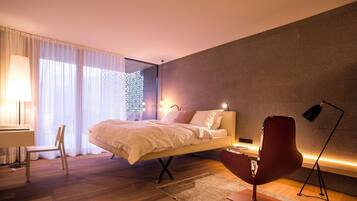 A modern bedroom with a bed, a desk, a chair, and a floor lamp.
