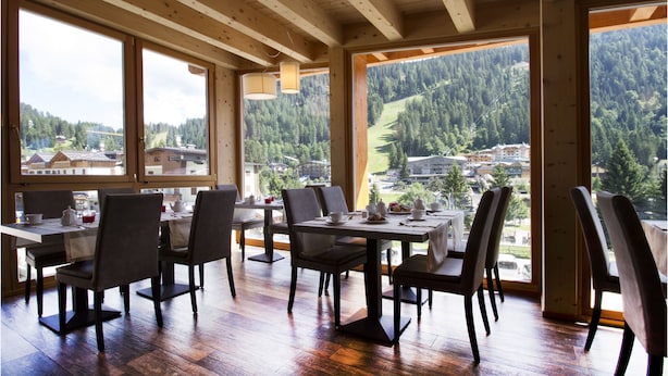 Un comedor con vigas de madera, ventanas amplias y vistas a un paisaje montañoso.