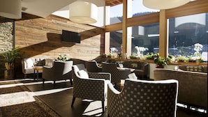 Un área de estar moderna con paredes de madera, ventanas amplias y un mobiliario confortable.
