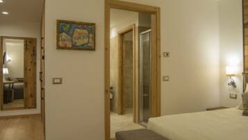 Une chambre à coucher avec un lit, un banc, un tableau et une porte donnant sur une salle de bain.