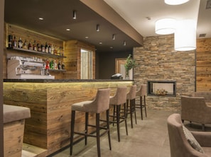 Een bar met houten barstoelen, een stenen muur en een open haard.