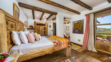 Un dormitorio rústico con una cama de madera, un ventanal con vistas y una araña.