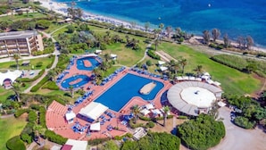 An aerial view of a resort with a large swimming pool, a beach, and a tennis court. - Hotel Baia Di Conte (Alghero)