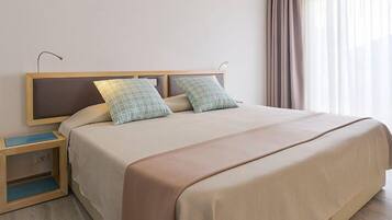 A neatly made bed with a headboard, two pillows, and a bedside table with a lamp.