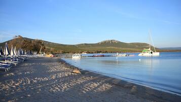 Ein Strand mit Liegestühlen und Booten im Wasser.