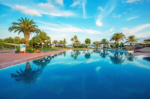 Una piscina al aire libre, sombrillas, tumbonas