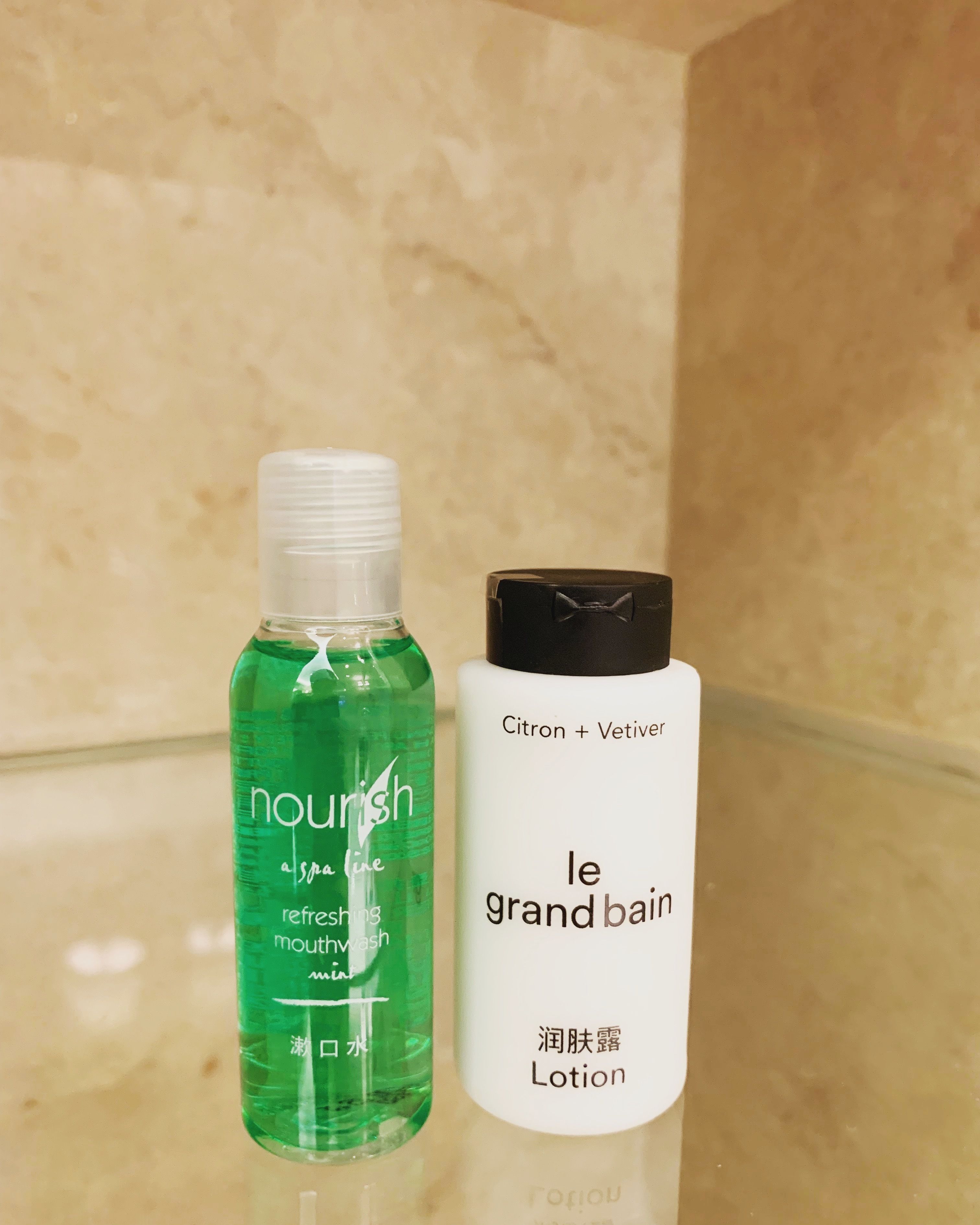 Dos frascos de productos para el cuidado de la piel sobre una superficie reflectante.