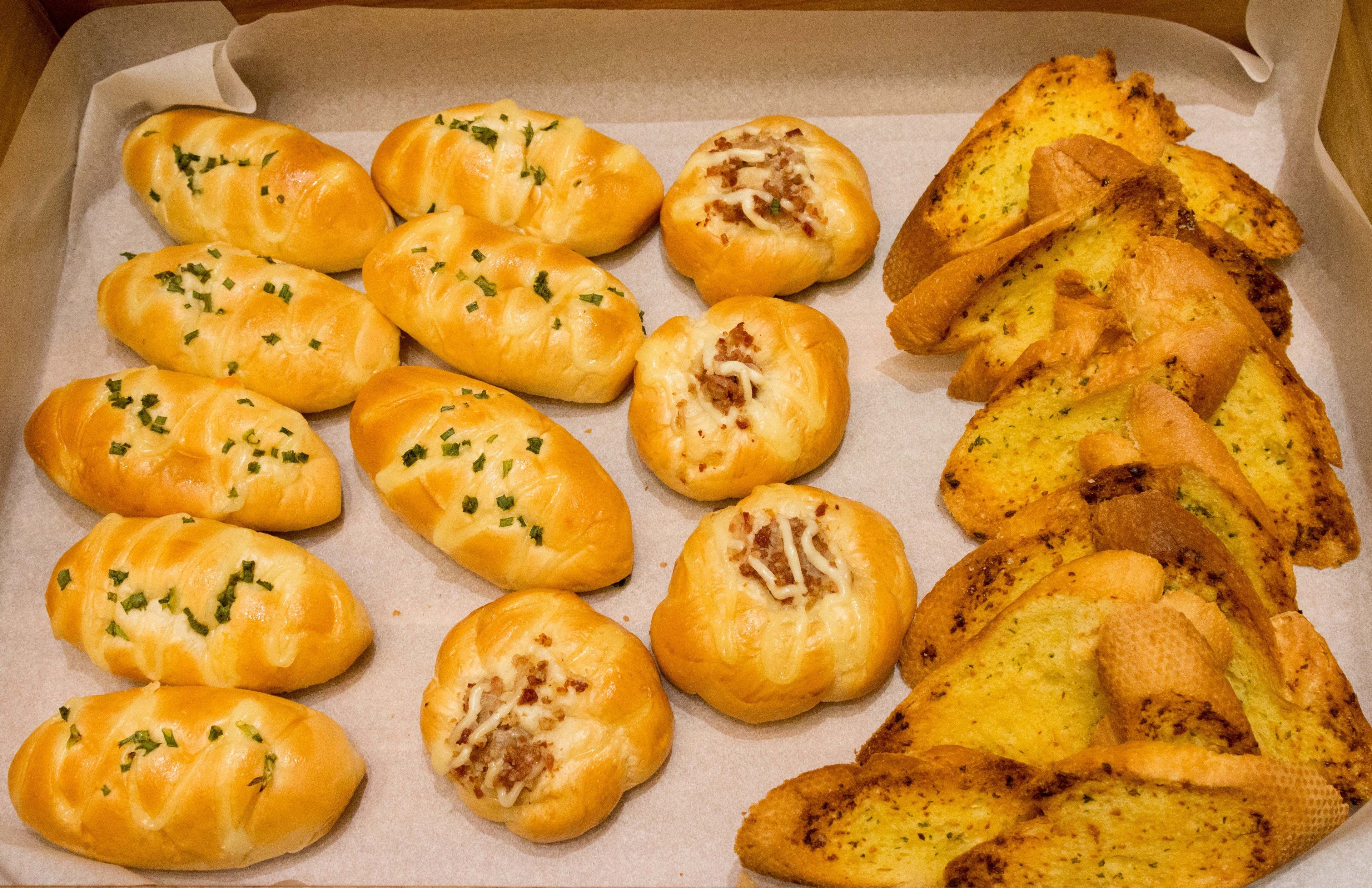 Una bandeja con productos horneados, incluyendo croissants y panecillos, sobre papel de hornear.