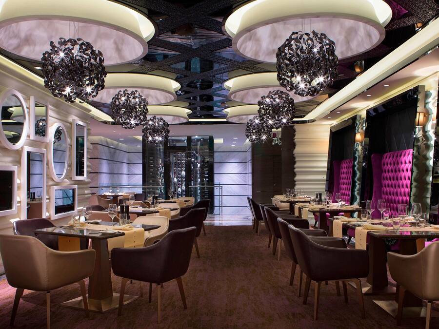 A modern restaurant with multiple dining tables, chairs, and unique spherical chandeliers.