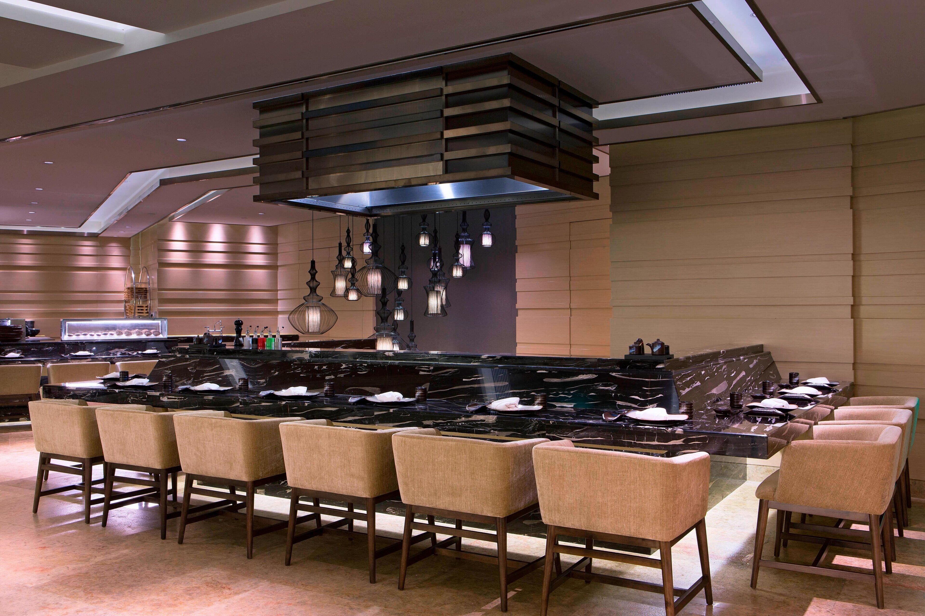 Una cocina moderna con una isla central, asientos tipo bar e iluminación colgante.