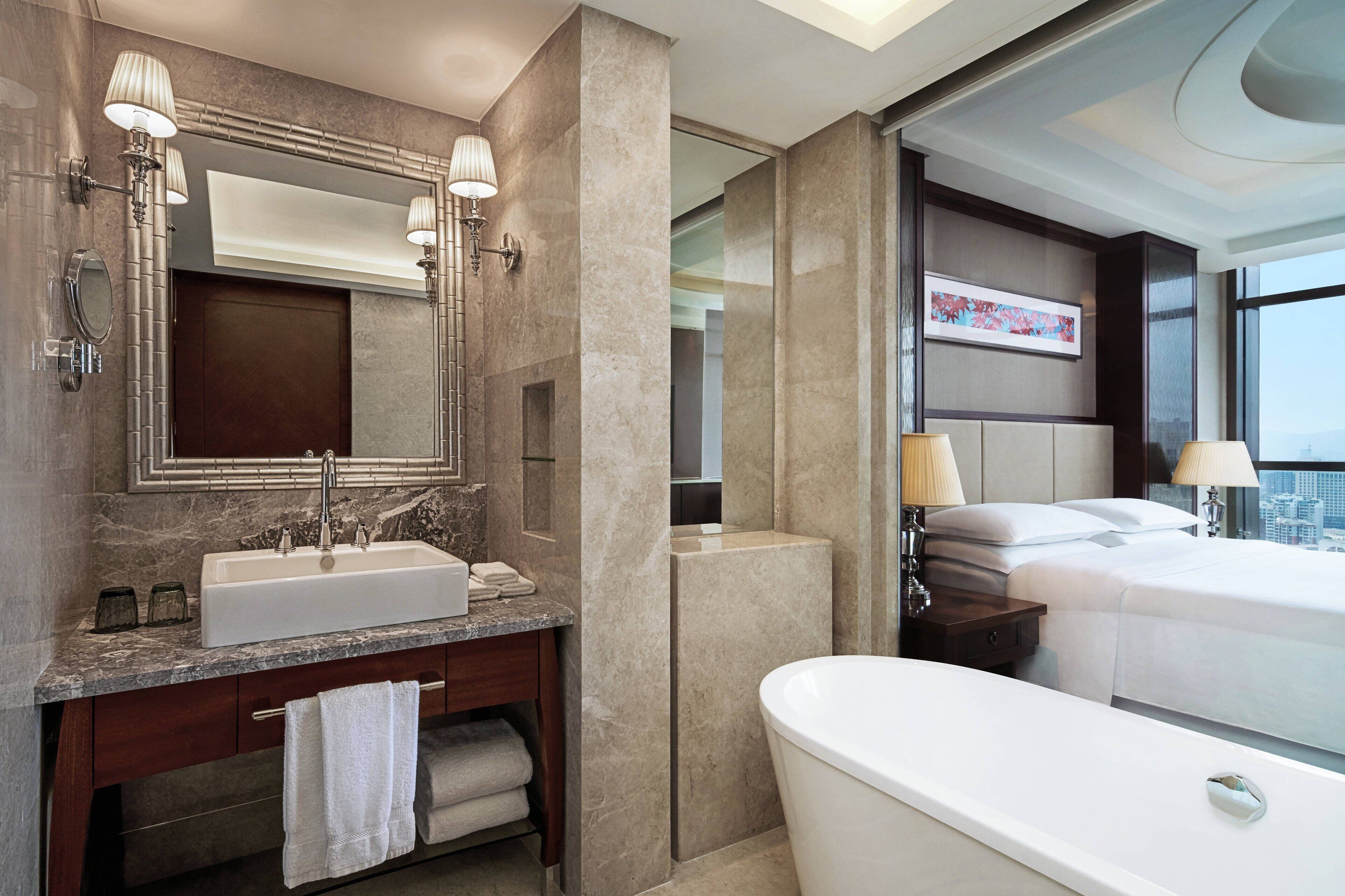 A modern bathroom with a large sink, mirror, and bathtub.