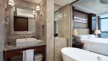 A modern bathroom with a large sink, mirror, and bathtub.