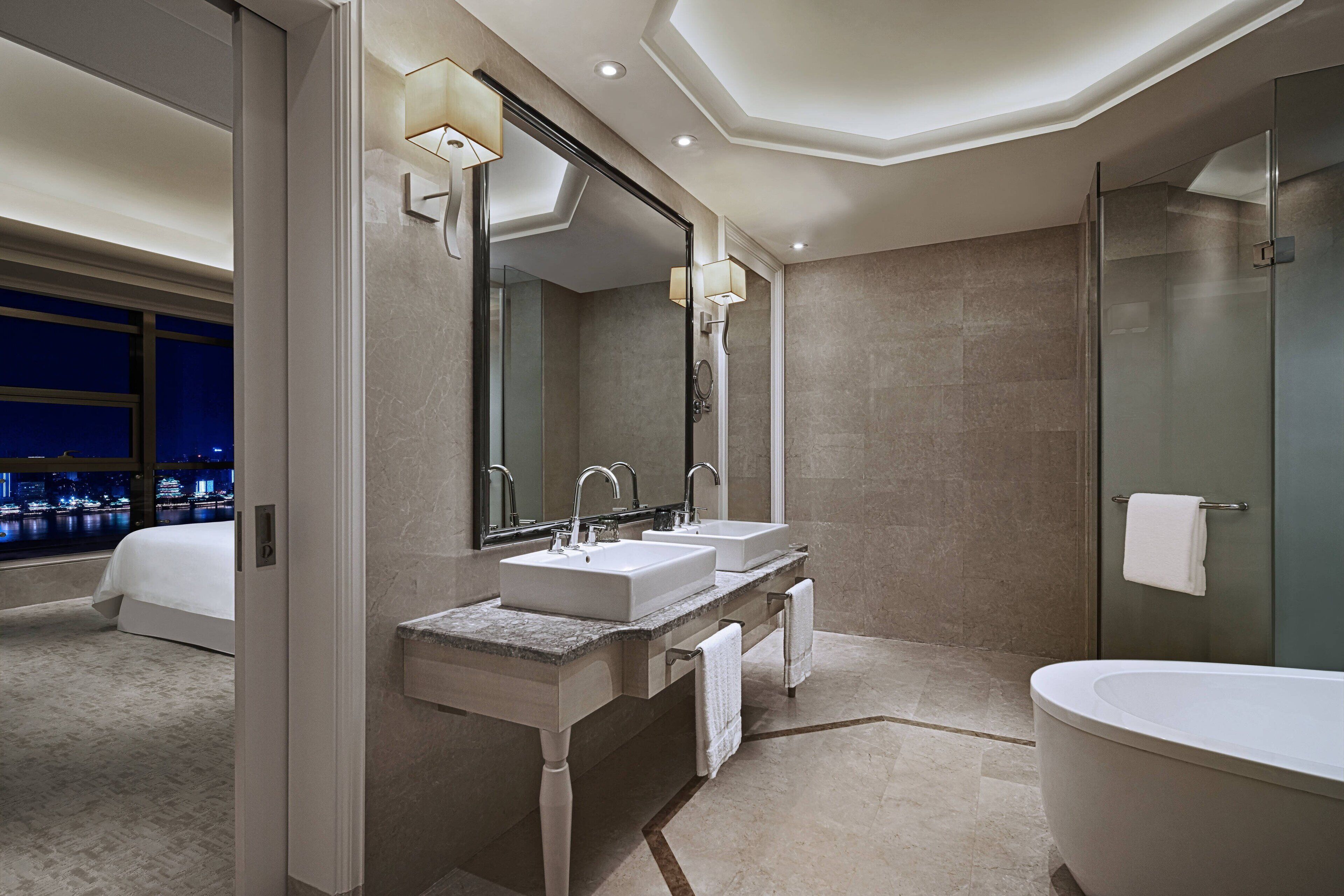 A modern bathroom with two sinks, a large bathtub, and a glass-enclosed shower.