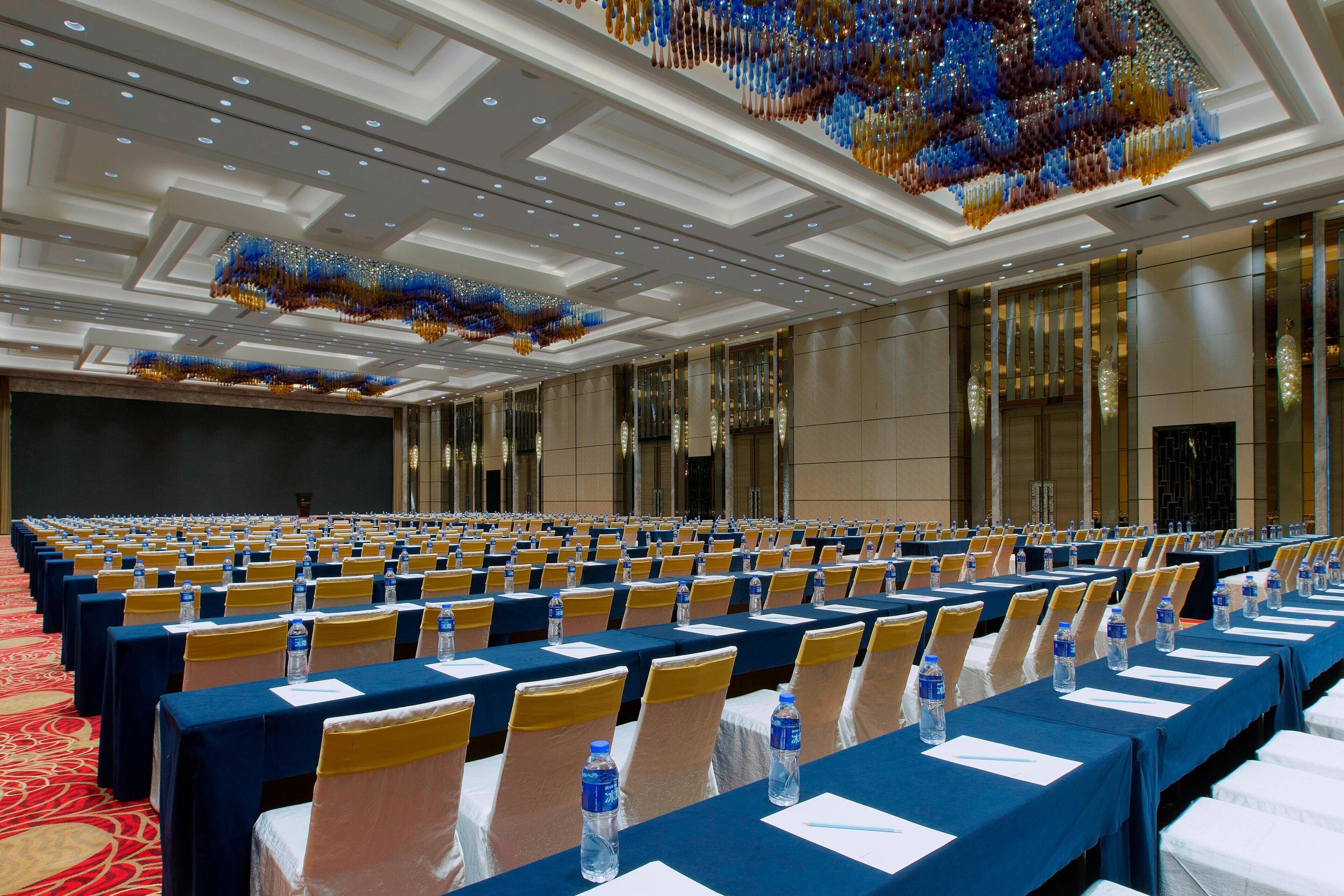A conference room with rows of tables, chairs, and water bottles.