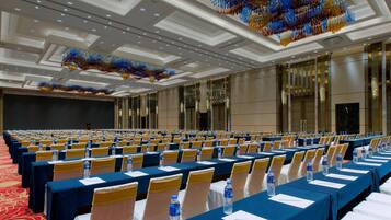 A conference room with rows of tables, chairs, and water bottles.