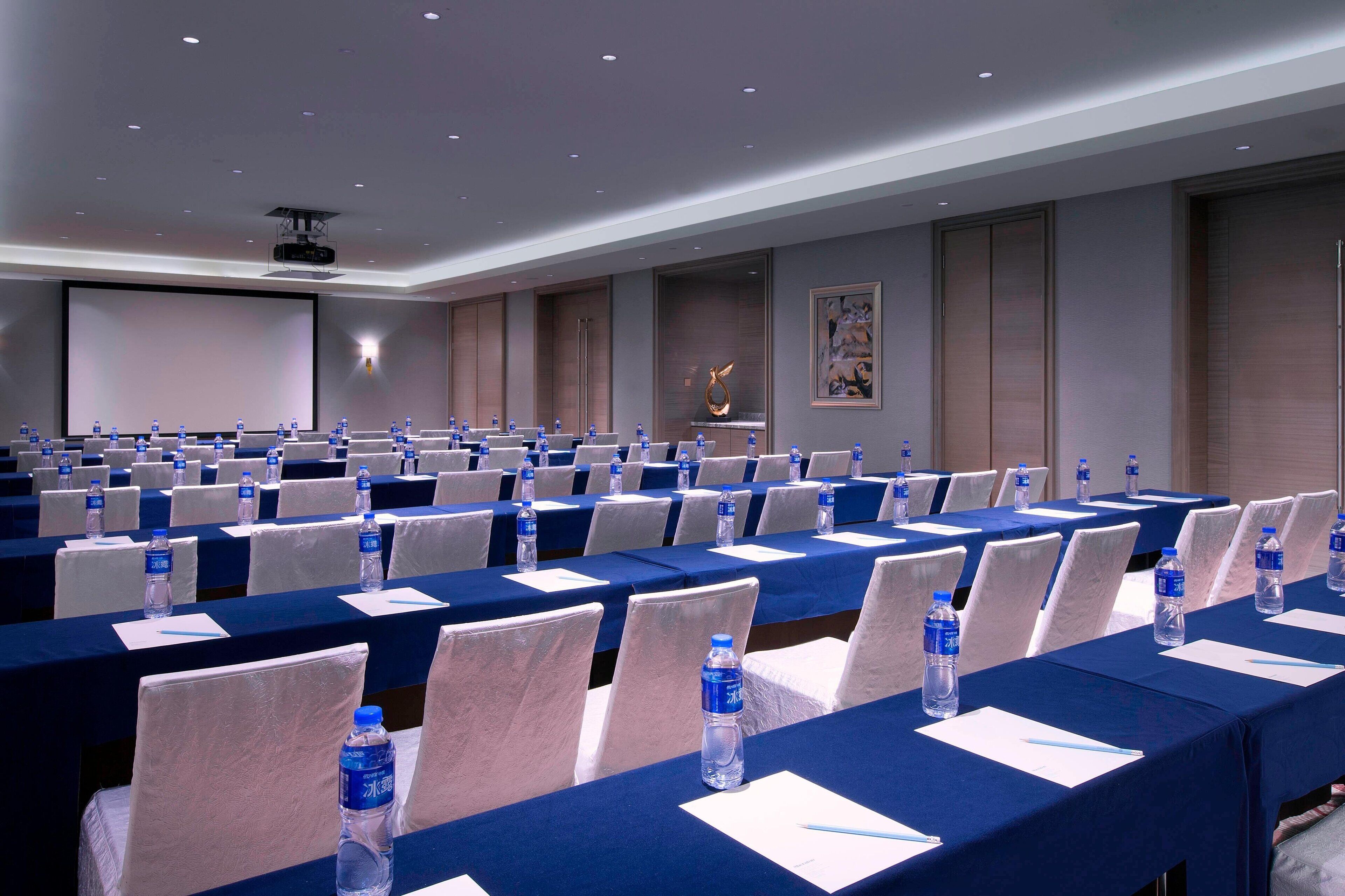 A conference room with rows of tables, chairs, and water bottles.