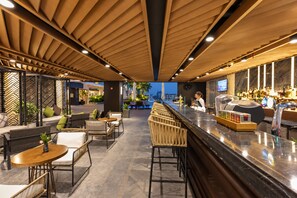 A bar area with seating, a counter, and a view of the outside. - Crowne Plaza Vientiane by IHG (Vientiane)