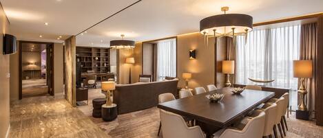 Una habitación de hotel moderna con zona de comedor, mostrador de recepción y vistas a la ciudad.