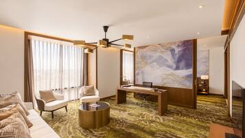 A modern hotel room with a sofa, chairs, a desk, and a large abstract painting on the wall.