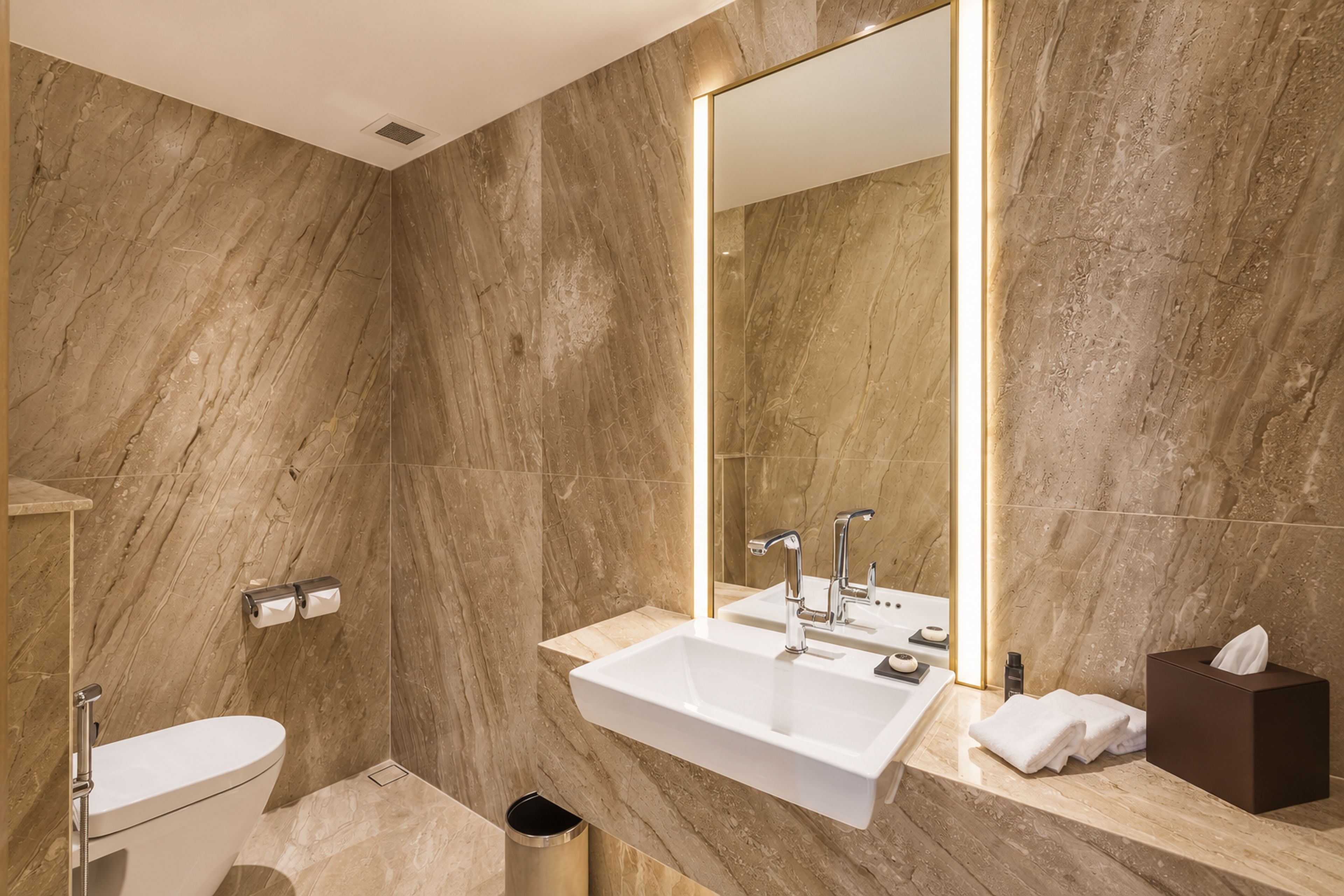 Un baño moderno con un espejo grande, un lavamanos blanco y un inodoro.