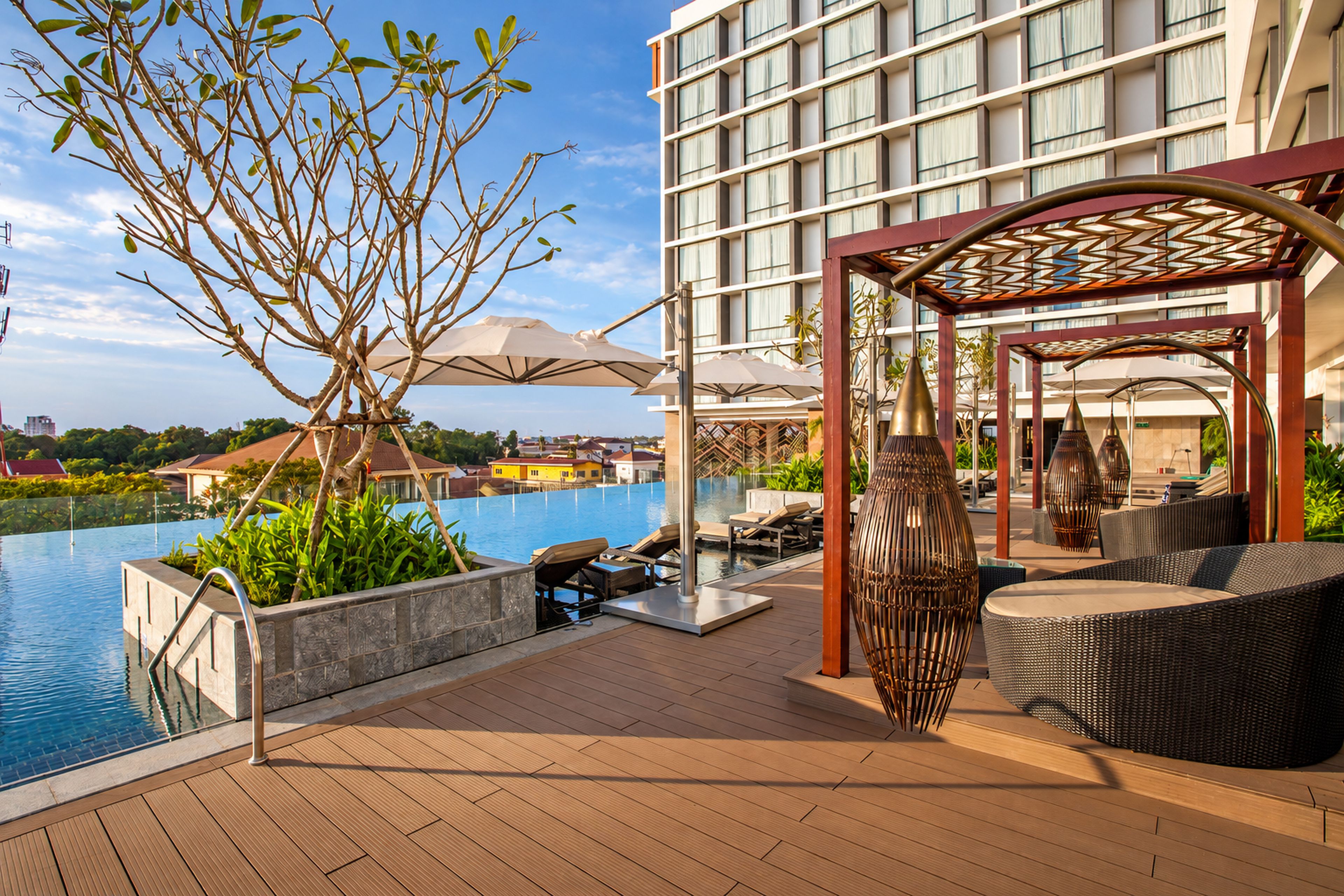 A poolside area with lounge chairs, a pergola, and a view of a building in the background.