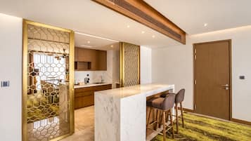 Una cocina moderna con encimera de mármol, armarios de madera y un separador decorativo hexagonal.