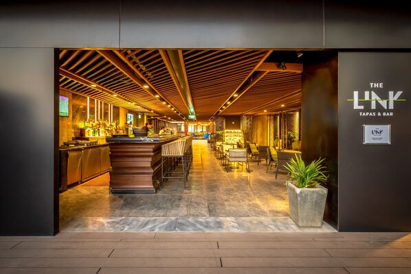 A modern bar area with a wooden ceiling, bar counter, seating, and a sign reading "THE LINK TAPAS & BAR". - Crowne Plaza Vientiane by IHG (Vientiane)