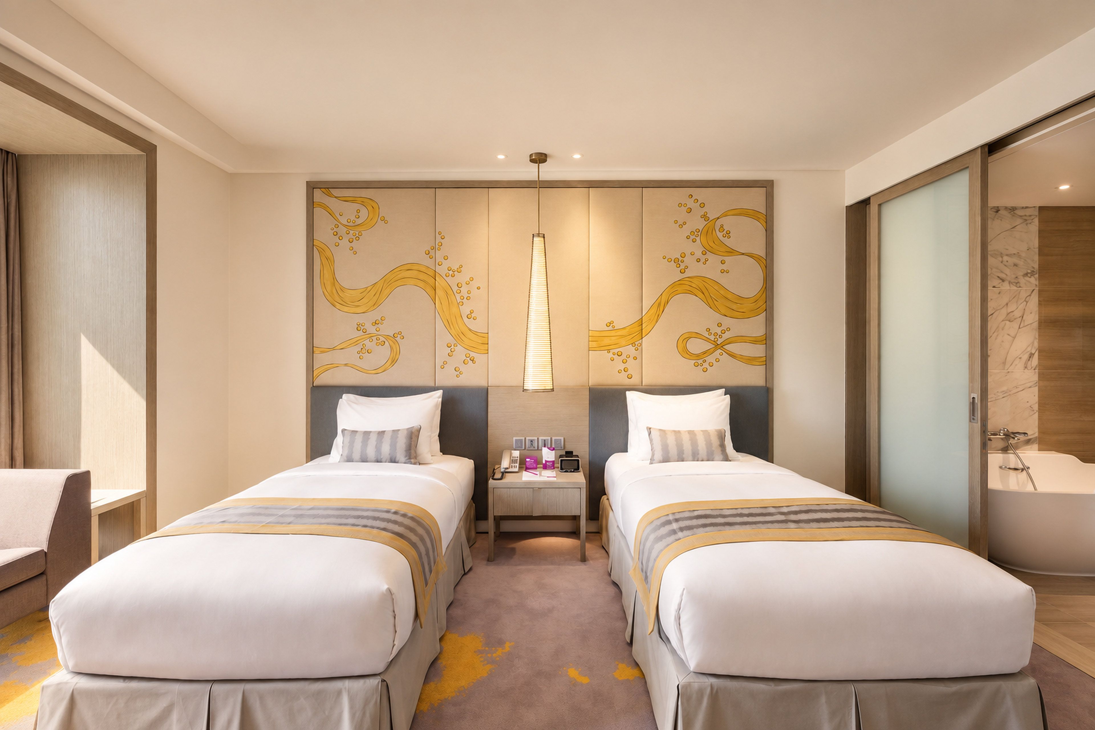 A hotel room with two beds, a bedside table with a lamp, and a large artwork on the wall.