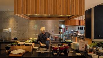 A chef preparing food in a modern kitchen with wooden cabinets and a tiled backsplash.