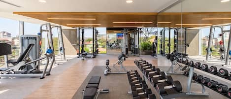Un gimnasio moderno con varios equipos de ejercicio, incluyendo cintas de correr, máquinas de pesas y mancuernas.