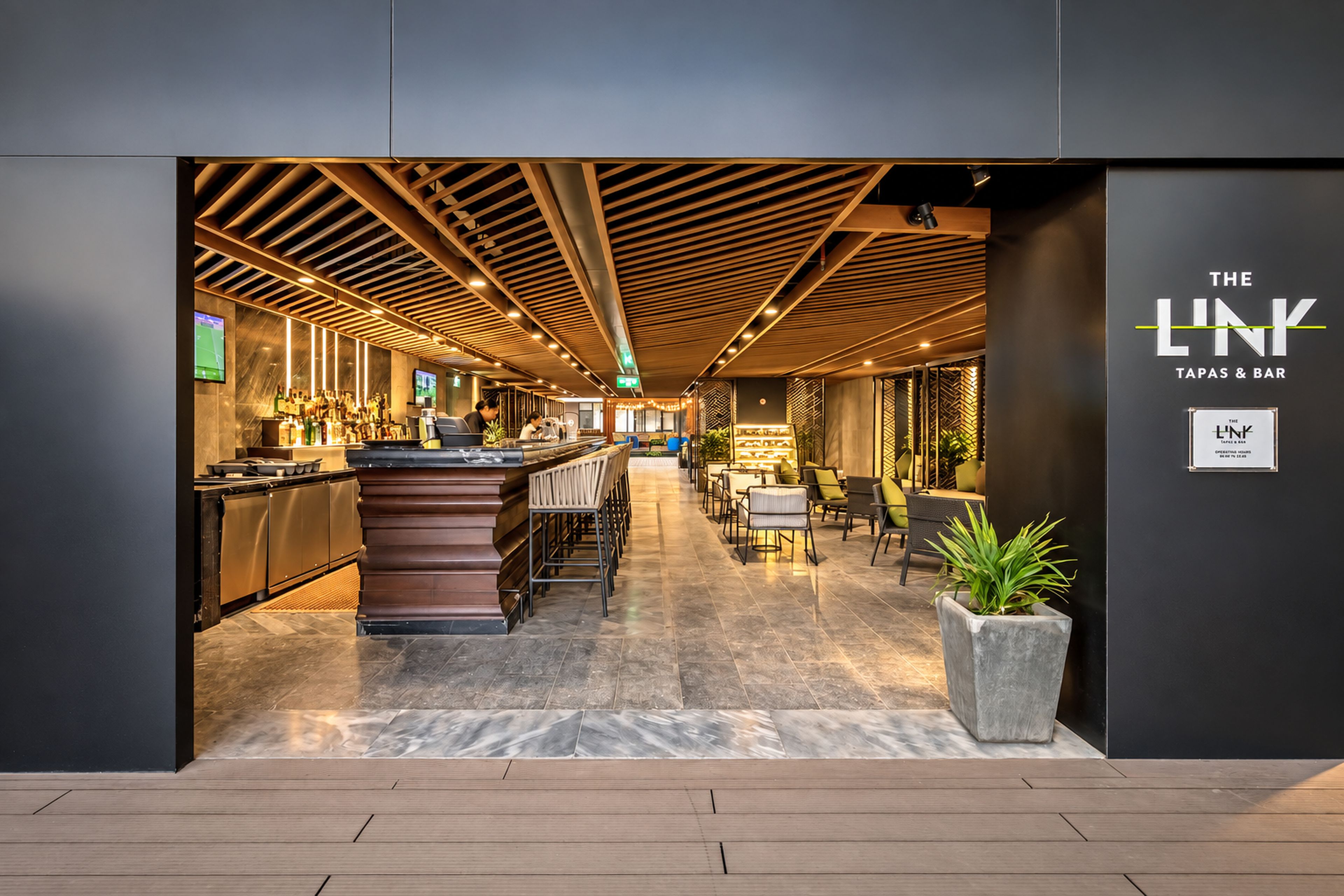 A modern bar area with a counter, seating, and a sign for 'The Link Tapas & Bar'.