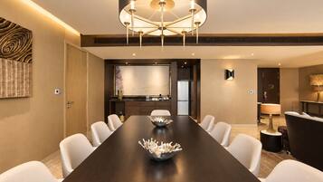 A modern conference room with a long table, white chairs, a decorative bowl, and a unique ceiling light fixture.