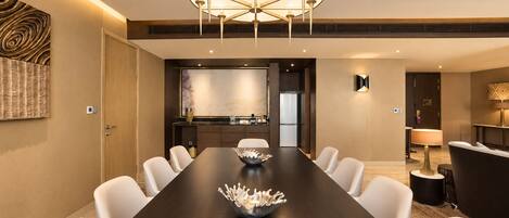 A modern conference room with a long table, white chairs, a decorative bowl, and a unique ceiling light fixture.