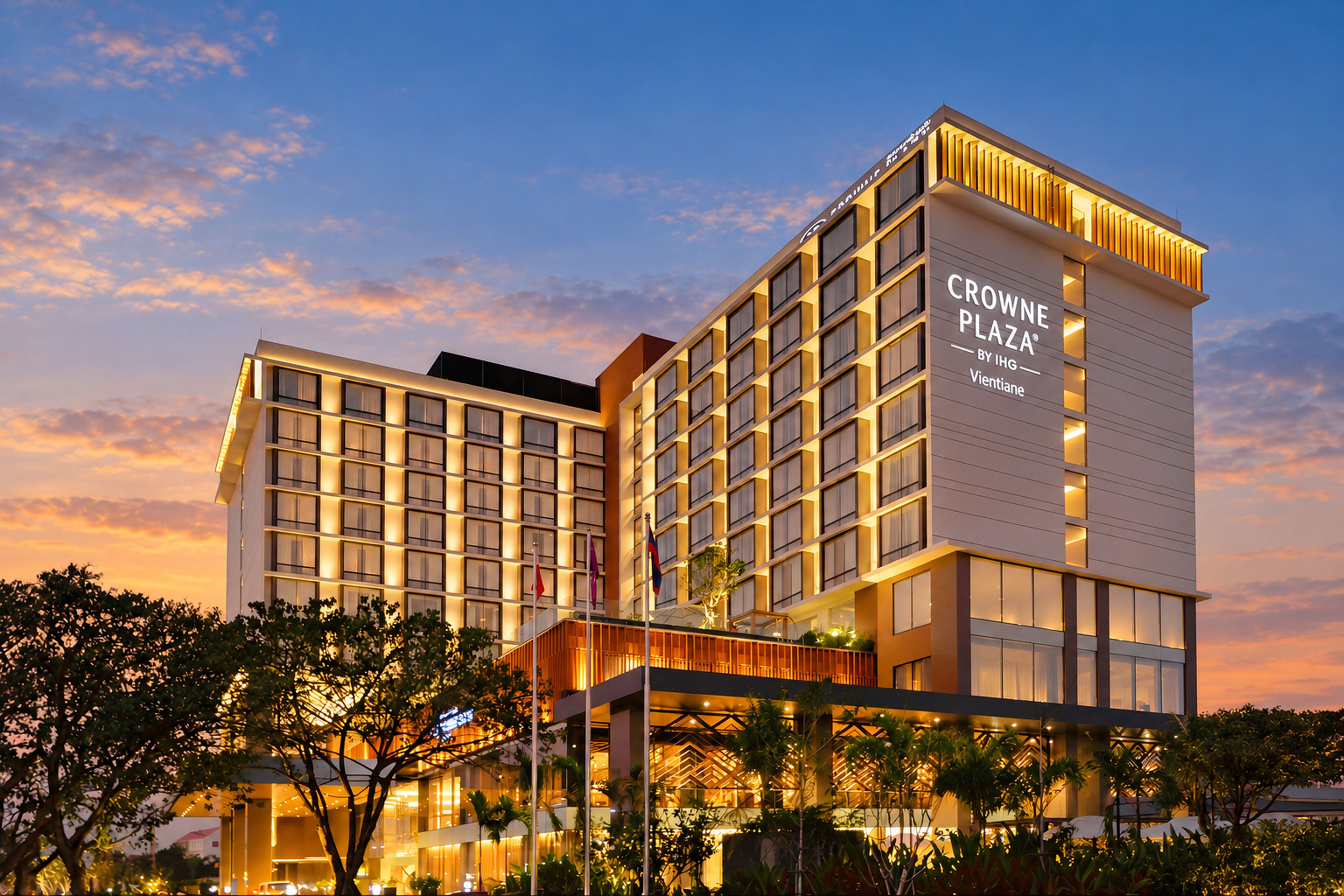 Un moderno edificio de hotel con varios pisos y un cartel llamativo que dice 'CROWNE PLAZA BY IHG Vientiane'.