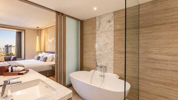A modern bathroom with a freestanding bathtub, a large mirror, and a view of the city.