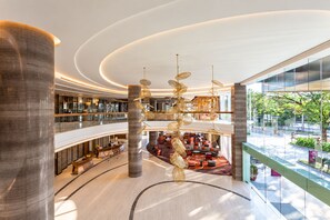 A modern hotel lobby with a central atrium, multiple floors, and a view of the outdoors. - Crowne Plaza Vientiane by IHG (Vientiane)