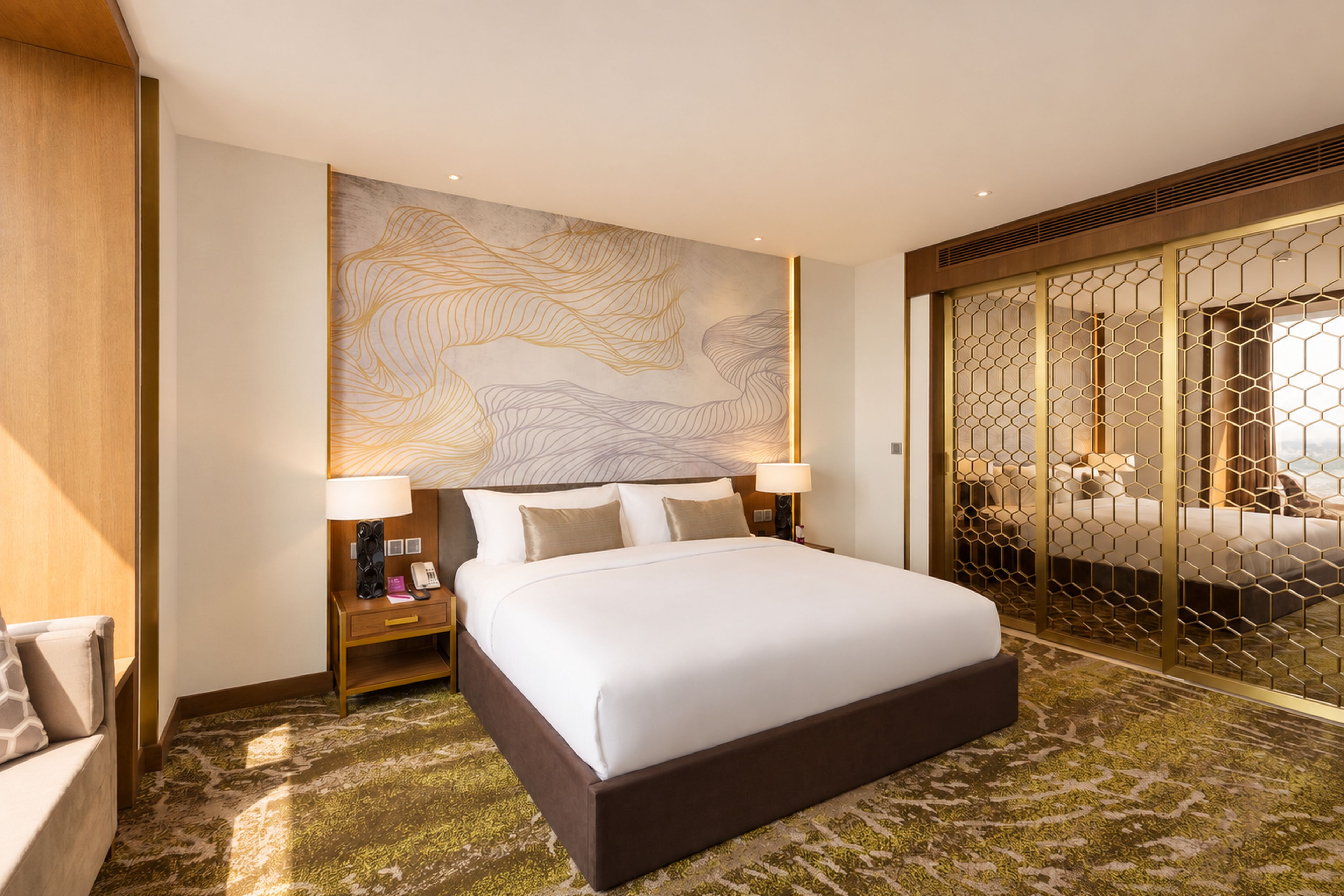 A hotel room with a large bed, a nightstand, a wall-mounted lamp, and a decorative wall panel.