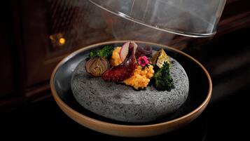 A plate of food with various items including a mushroom, a piece of meat, and some greens.