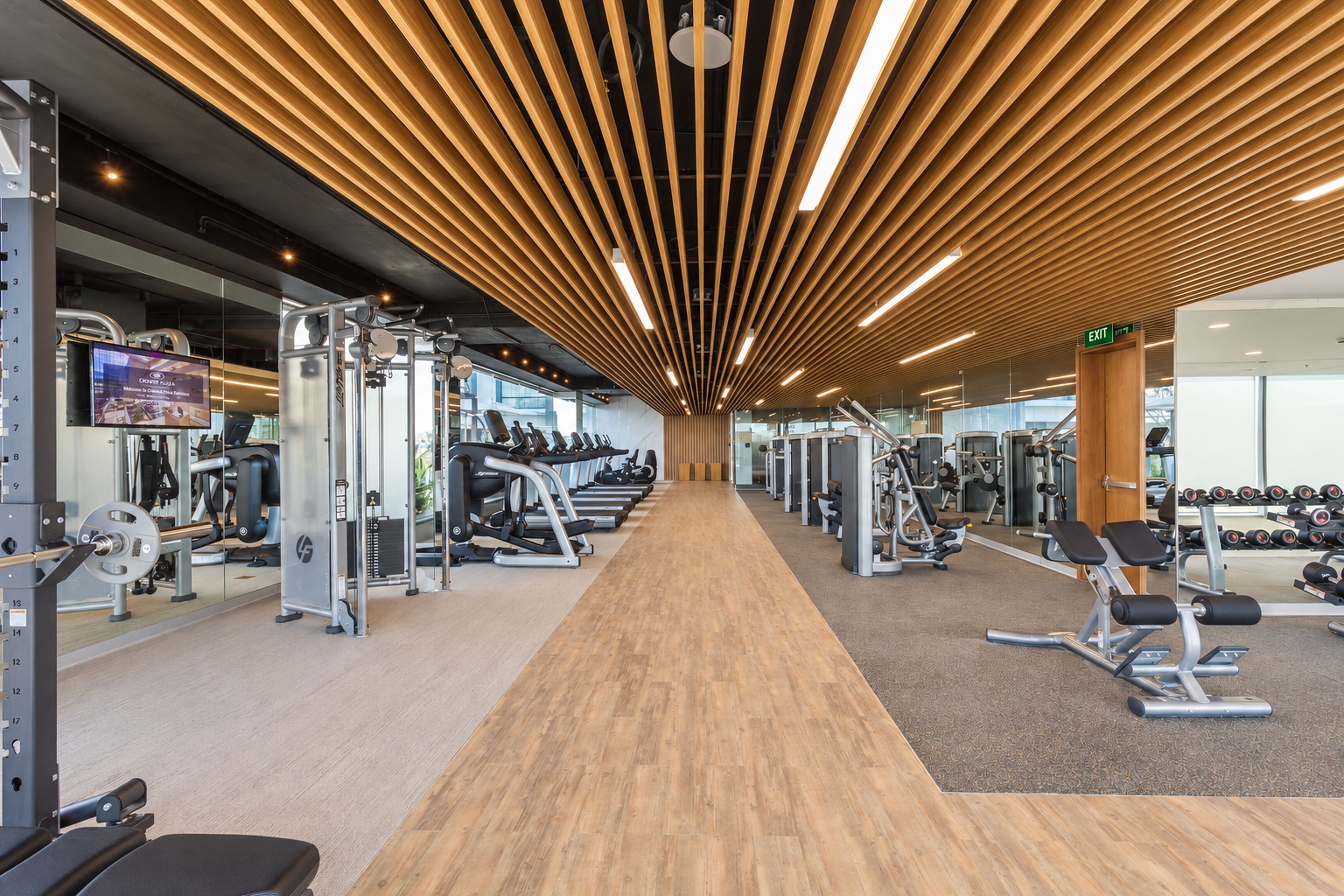 Une salle de sport dotée d’un plancher en bois, d’appareils d’exercice et d’un écran de télévision affichant un message de bienvenue.