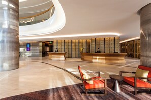 A modern hotel lobby with a curved reception desk, seating area, and a spiral staircase. - Crowne Plaza Vientiane by IHG (Vientiane)