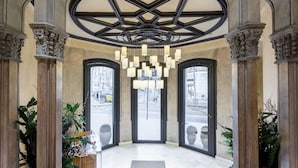 En lobby med et geometrisk loftdesign, store vinduer og en central lysekrone.
