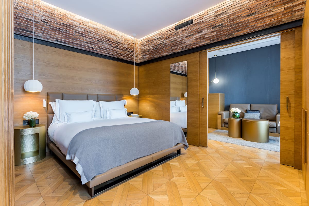 Un dormitorio moderno con una cama grande, cabecero de madera y una pared de ladrillo decorativa.
